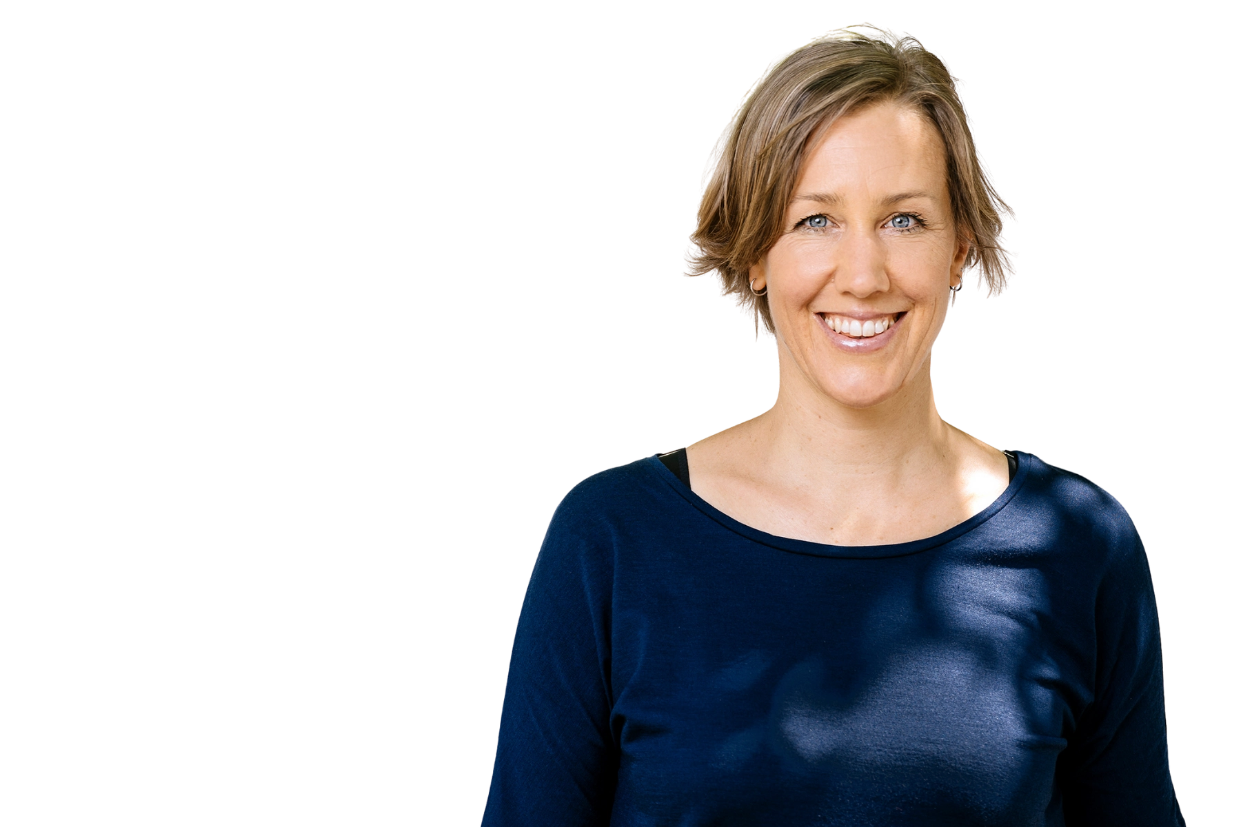 Professionelles Portrait von Anna Yona, Gründerin von Wildling Shoes, mit kurzen blonden Haaren und dunklem Oberteil vor weißem Hintergrund, lächelnd in die Kamera blickend.