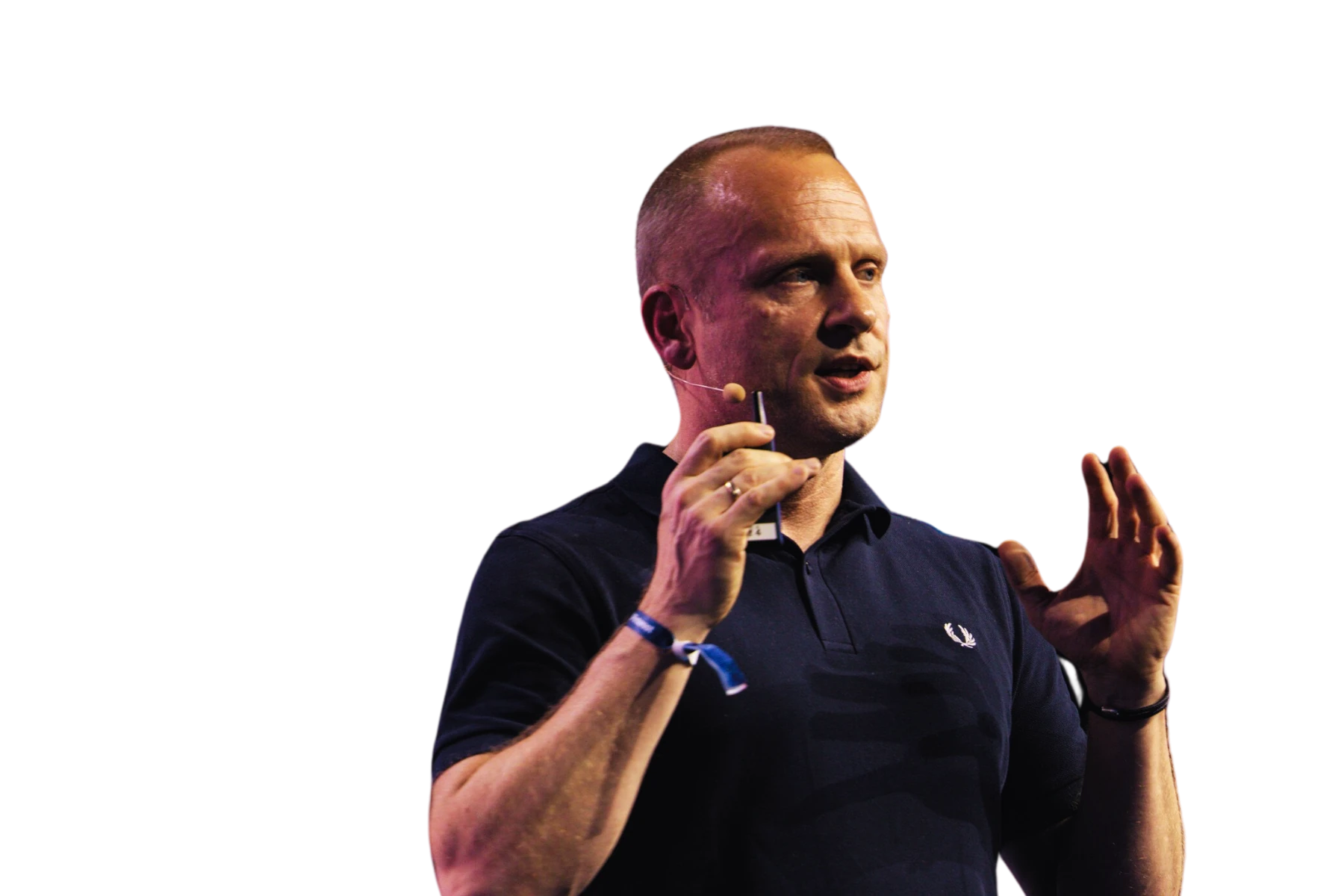 Freisteller von Bastian Siebers, CEO von flaconi, im dunkelblauen Poloshirt mit Headset-Mikrofon vor schwarzem Hintergrund. Er spricht gestikulierend auf der Bühne und hält einen Presenter in der Hand – Keynote-Speaker der K5 CHEF TREFF Jubiläumsfolge 250 über Wachstum und Transformation bei flaconi.