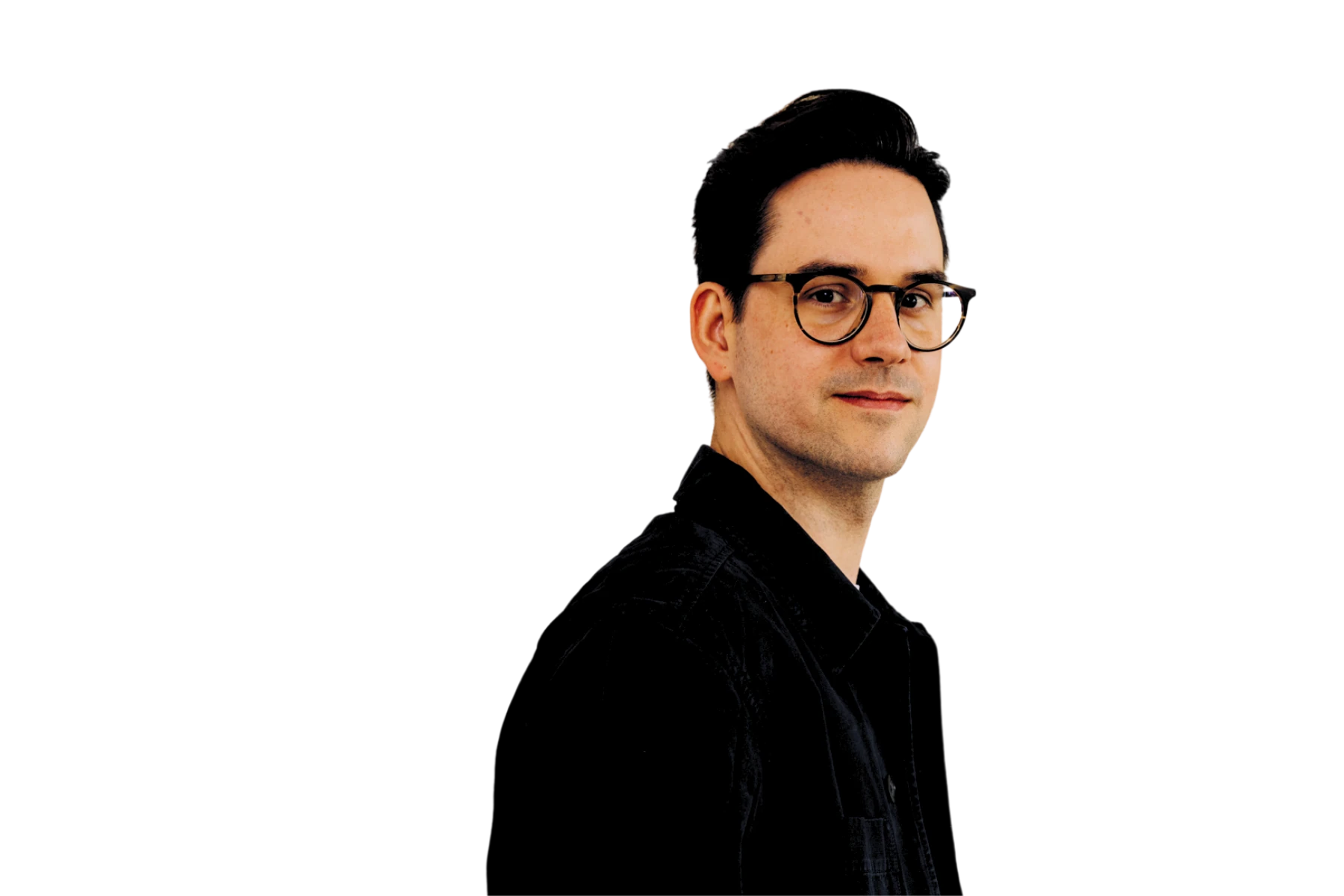 Freisteller von Alexander Hefele, Co‑Founder & CEO von Naturkosmetik München (nkm), im schwarzen Hemd und mit runder Brille vor schwarzem Hintergrund, leicht im Profil nach rechts blickend – Gesicht der K5 COMMERCE CAST Episode 180 über Omnichannel, Naturkosmetik und datengetriebige Hautpflege.