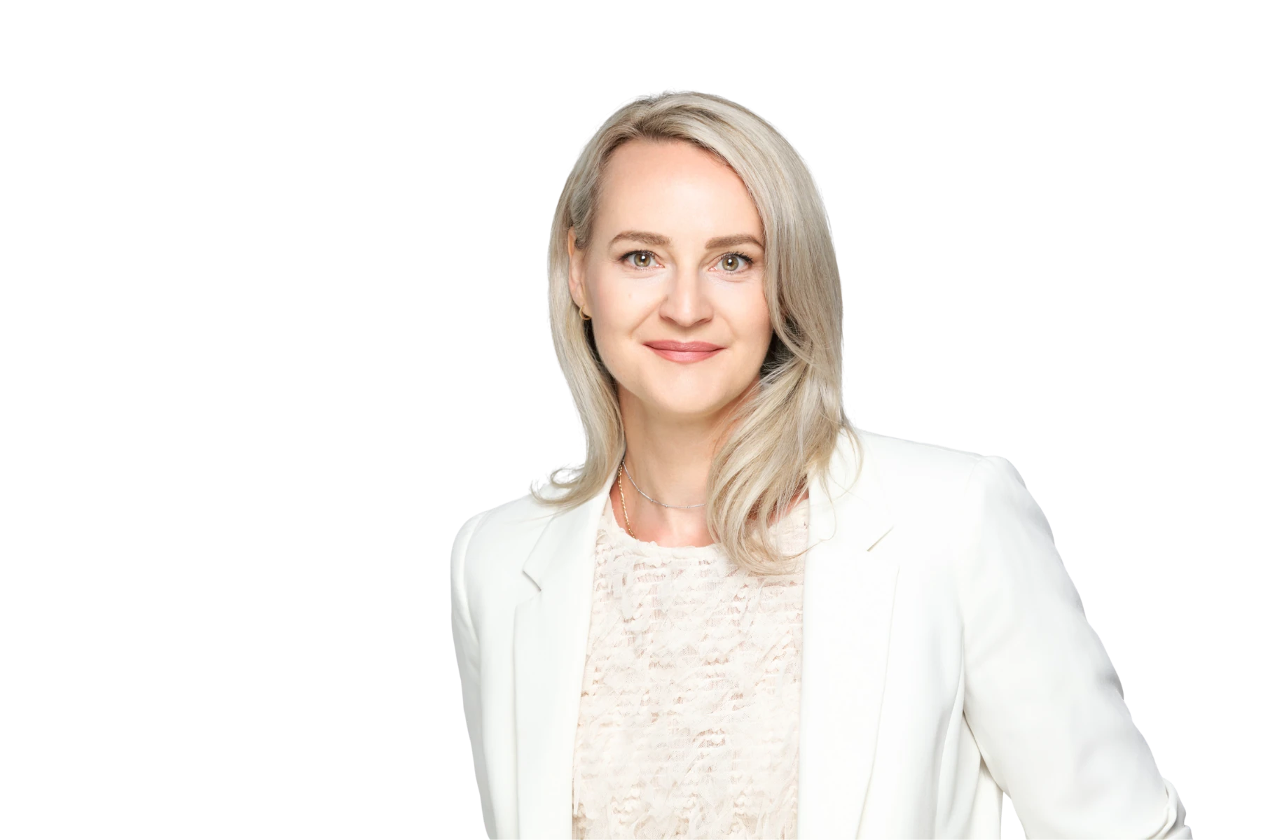 Professionelles Portrait von Mirja Rousselle, Vice President Global Marketing bei BABOR, mit blonden schulterlangen Haaren in weißem Blazer über cremefarbenem Spitzentop vor weißem Hintergrund, freundlich lächelnd. ©Denise Krentz.