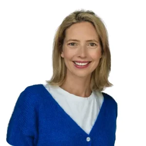 Business-Portr&auml;t von Nadine Bartenschlager mit blondem Haar in wei&szlig;em Shirt und blauem Strickcardigan vor wei&szlig;em Hintergrund