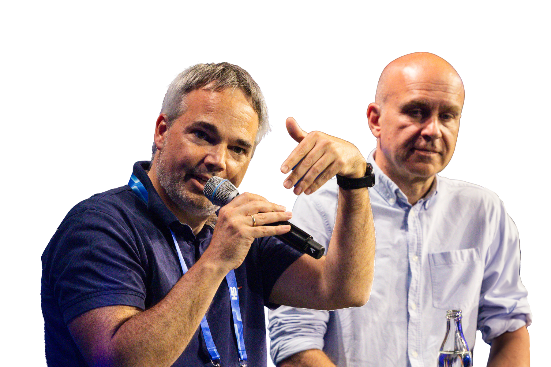 Jochen Krisch am Mikrofon in dunklem Poloshirt mit blauem Lanyard und Florian Heinemann in hellblauem Hemd auf der K5-Bühne während ihrer Live-Diskussion über den Zalando-About You-Merger vor weißem Hintergrund.