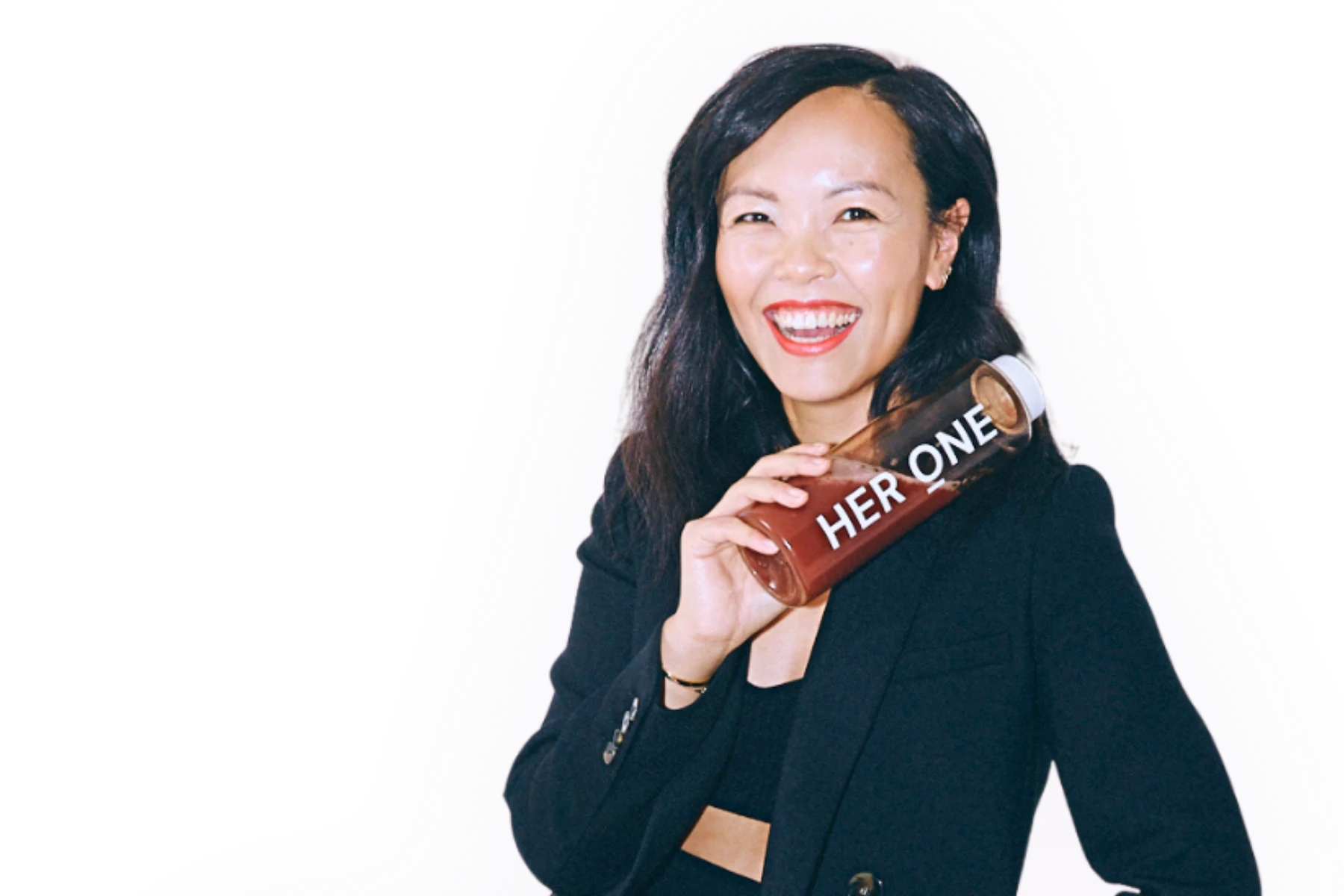 Freisteller-Porträt von Chanyu Xu, Gründerin und CEO von HER ONE. Sie lächelt breit, hält eine HER-ONE-Flasche in der Hand und trägt ein schwarzes Outfit. Um sie herum ist eine sanfte, farbige Kontur in Rosa- und Lilatönen.