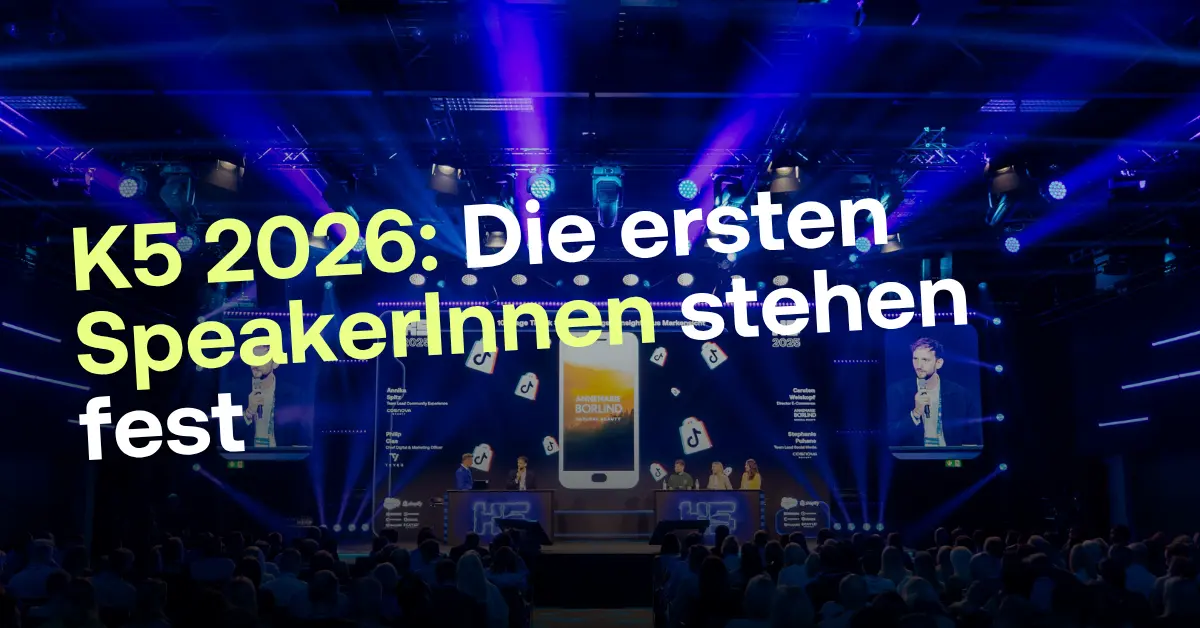 Das Bild zeigt eine dunkel beleuchtete B&uuml;hne mit blauem Scheinwerferlicht und einem gro&szlig;en Publikum im Vordergrund. &Uuml;ber dem Bild liegt der gro&szlig;e wei&szlig;e Text: &bdquo;K5 2026: Die ersten SpeakerInnen stehen fest&ldquo;. Im Hintergrund sind Bildschirme mit Portr&auml;ts von Sprechern, Firmenlogos wie TikTok und Annemarie B&ouml;rlind sowie eine Liste von Namen und Positionen der Referenten zu sehen. Auf der B&uuml;hne moderieren mehrere Personen an Pulten.