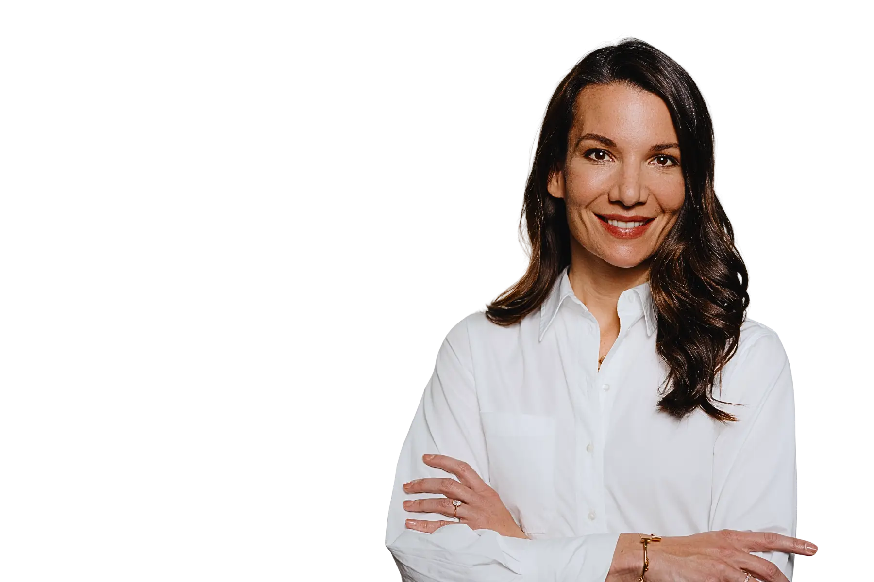 Freigestelltes Porträt von Dr. Sarah Bechstein. Sie trägt eine weiße Bluse, hat lange, braune, gewellte Haare und blickt mit einem offenen Lächeln und verschränkten Armen direkt in die Kamera. Der Hintergrund ist komplett schwarz.