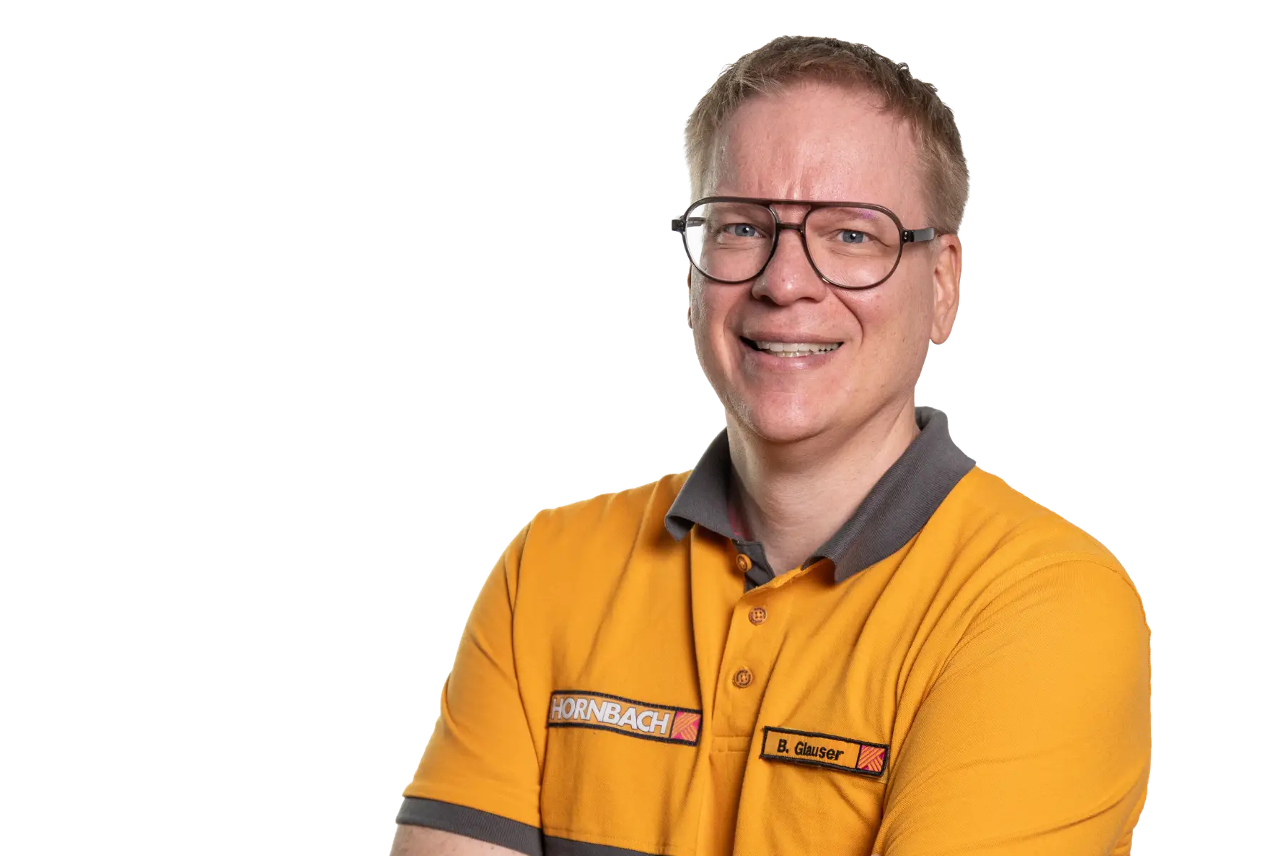Freigestelltes Porträt von Benjamin Glauser, Leiter E-Business Konzern bei HORNBACH. Er lächelt freundlich, trägt eine markante Brille und die HORNBACH-Arbeitskleidung mit seinem Namensschild.