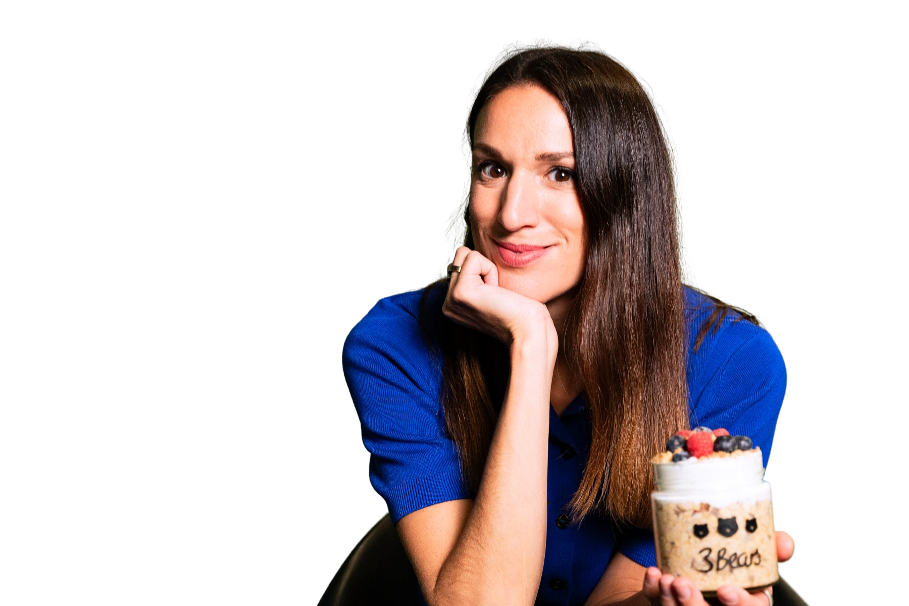 Porträt-Freisteller von Caroline Nichols, CEO von 3Bears, die Hand am Kinn abgestützt, mit einem Overnight-Oats-Produktglas vor schwarzem Hintergrund.