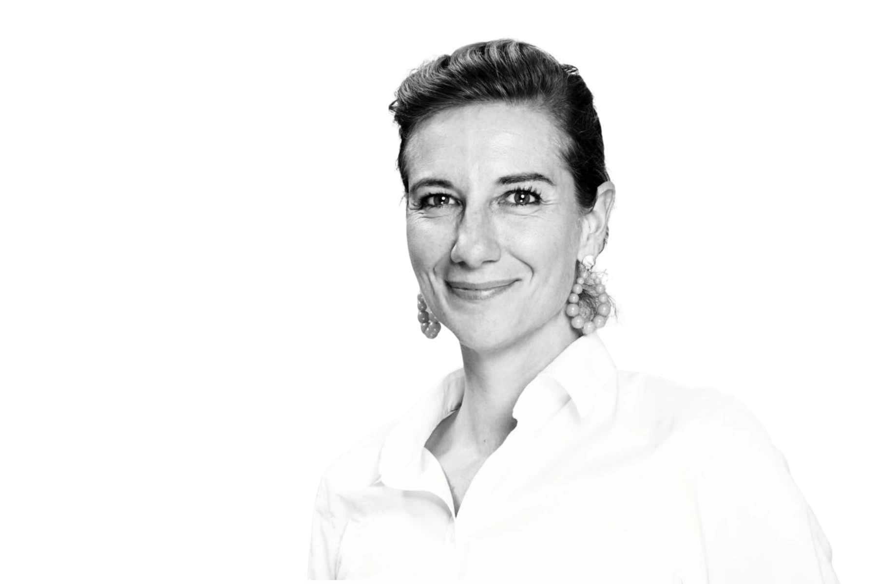 Schwarz-Weiß-Porträt als Freisteller von Sophie Friedl, COO bei Bassetti, lächelnd in einer weißen Bluse mit auffälligen Ohrringen vor weißem Hintergrund.