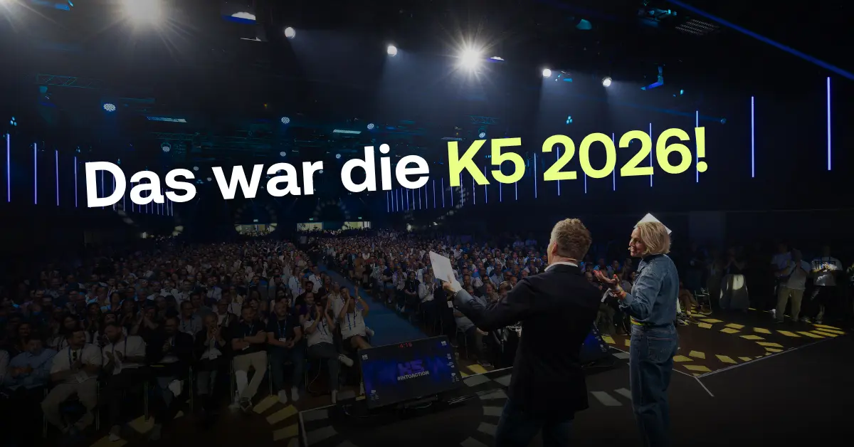 Blick von einer K5-B&uuml;hne auf ein riesiges, applaudierendes Publikum in einer gro&szlig;en Konzerthalle. Im Vordergrund stehen zwei Moderatoren von hinten auf der B&uuml;hne und blicken in den Saal.